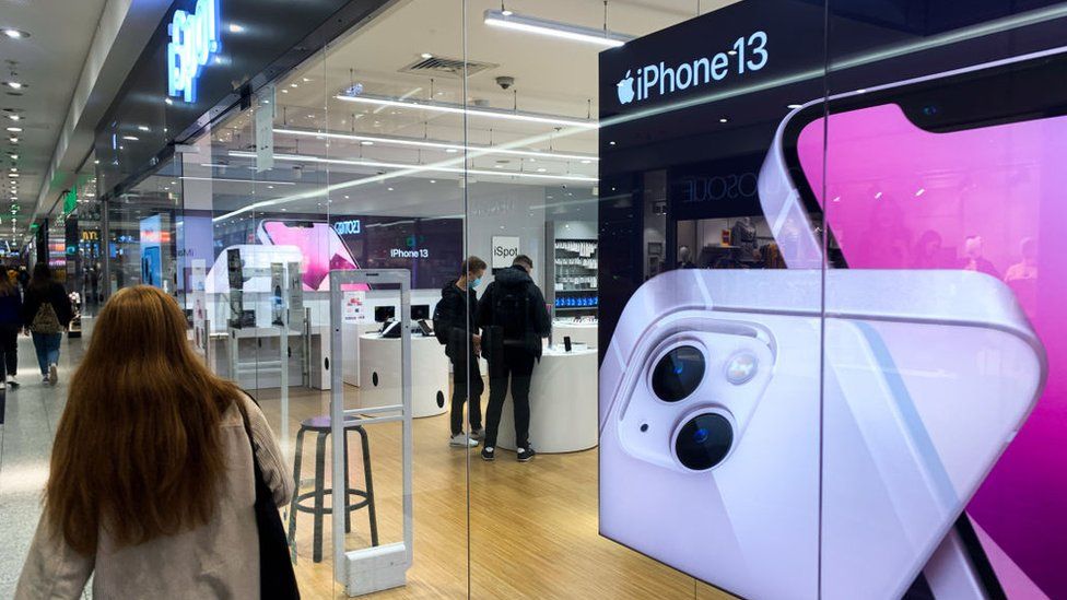 A woman walks past a store advertising the iPhone 13 in Poland
