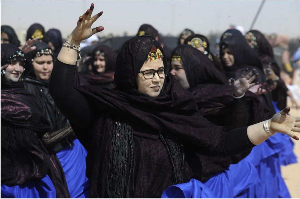 Sahrawi women wearing black headscarves with what appears to be blue wrappers.