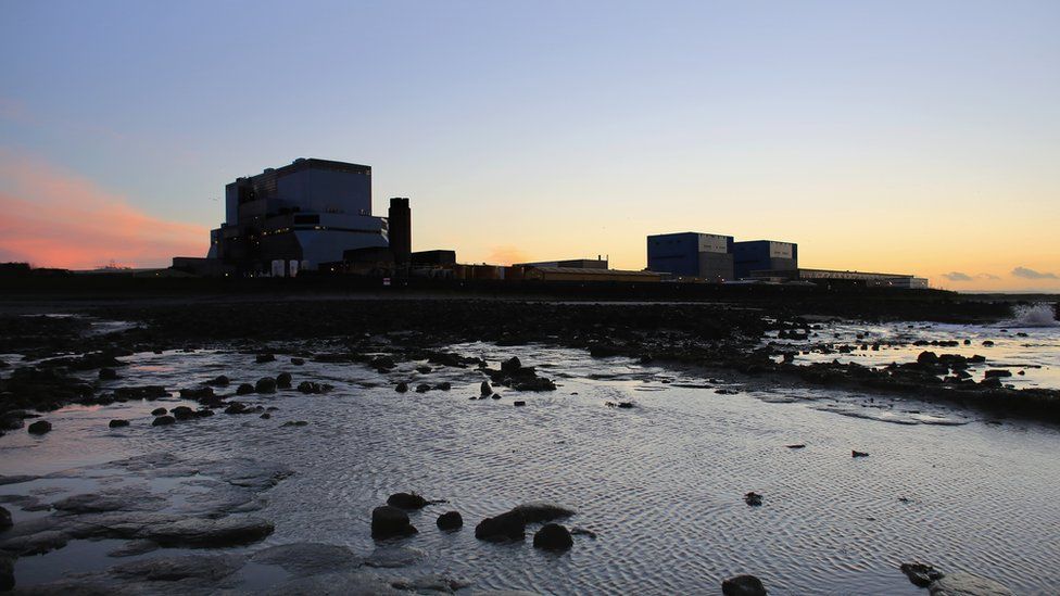 The sun sets behind Electricite de France SA's (EDF) (L) Hinkley Point B, and (R) Hinkley Point A nuclear power stations