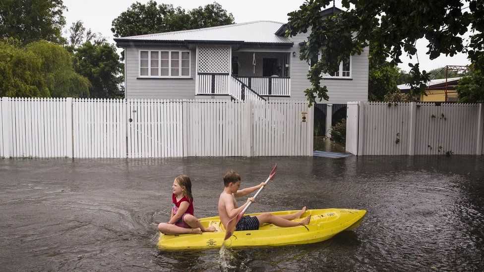 Nosh and Charlotte Talbot paddle down Queens Road during flooding in Rosslea