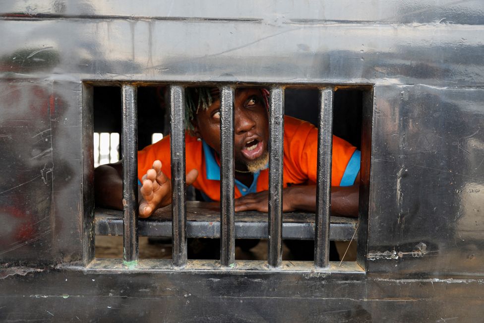 Жагсагчид 2022 оны 10-р сарын 20-ны өдөр Нигерийн Лагос хотод цагдаагийн фургонд баривчлагдан хоригдож буйд хариу үйлдэл үзүүлж байна.