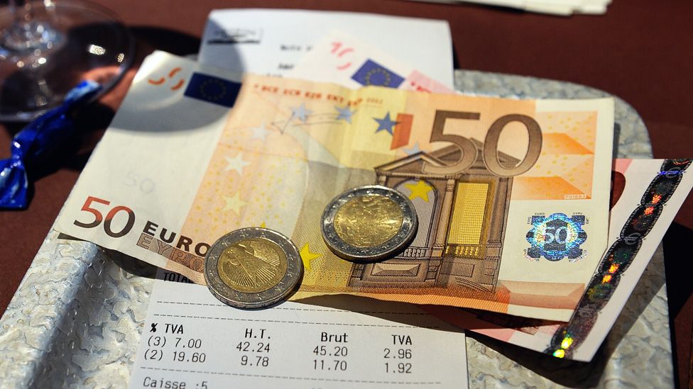Euro notes and coins on a restaurant table, paying a bill.