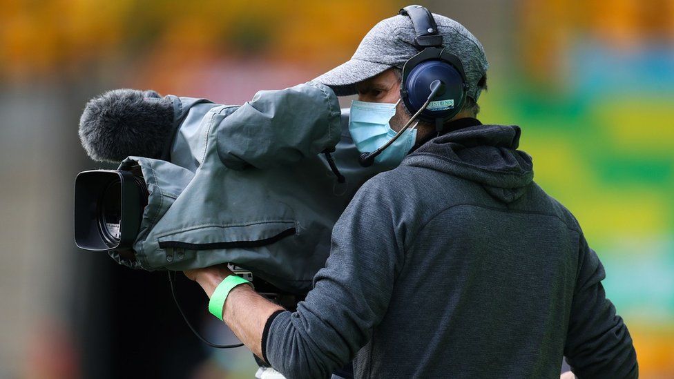 A camera operator wears a face mask as he films at a football match in Norwich