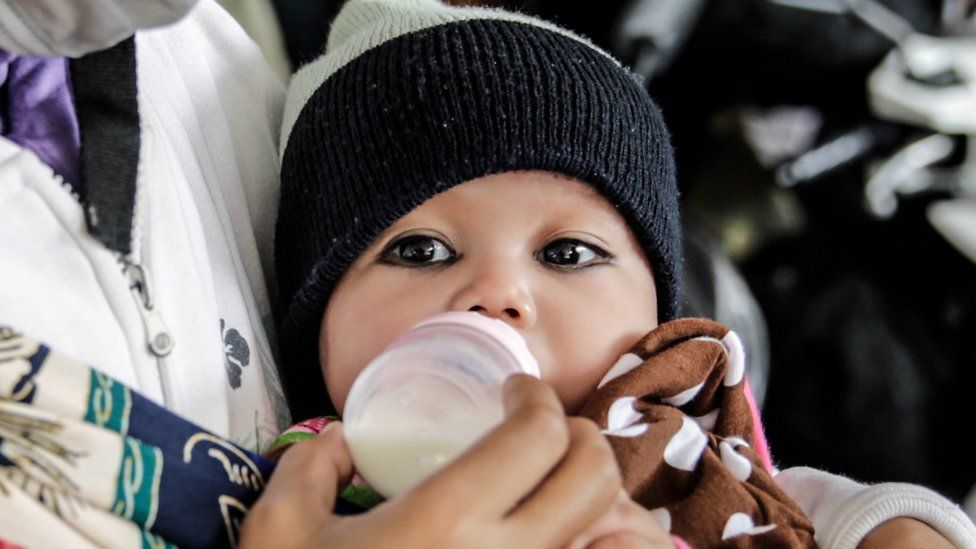 A baby drinks milk from a bottle