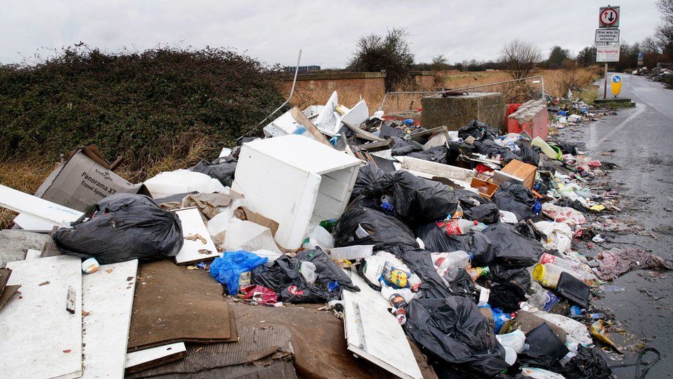 Piles of fly-tipped material at the side of a road