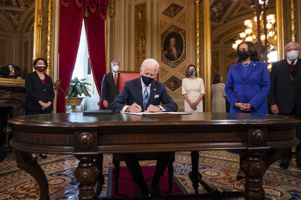 President Biden signs documents with Vice President Kamala Harris by his side