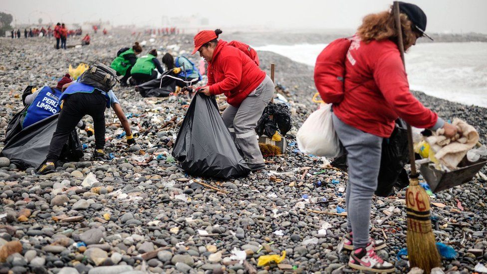 Groups of volunteers clean up plastic waste on a beach