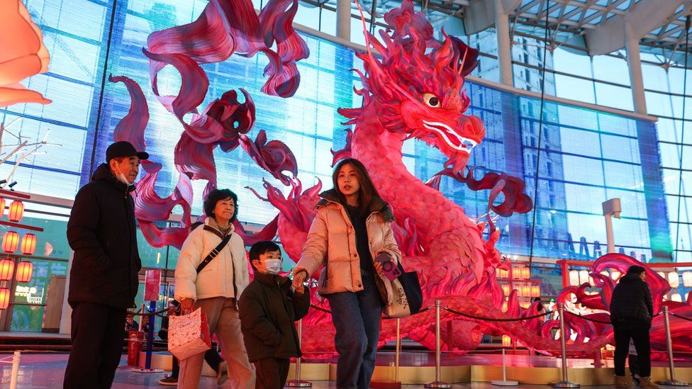 People walk by a dragon lantern in a shopping centre in Beijing, China