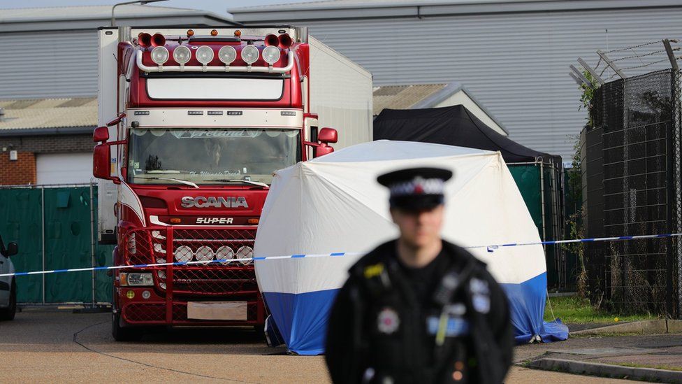 A police officer stands watch in front of the lorry