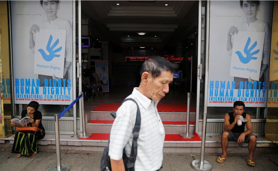 A man walks in front of the Naypyitaw Cinema in Yangon, with Human Rights Human Dignity International Film Festival posters displayed in its front windows, on 15 June 2016.