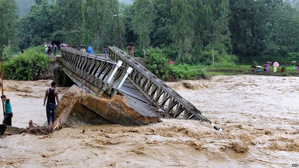 People look at the bridge which was washed away by the floodwaters in Thoubal District in Manipur state on August 1, 2015