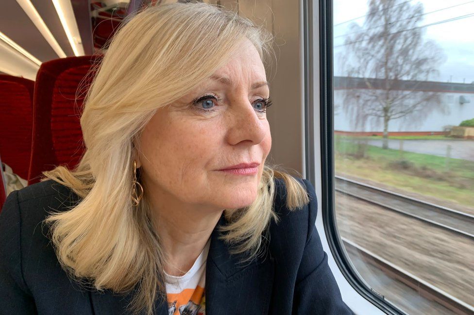 A woman sits on a train looking out the window