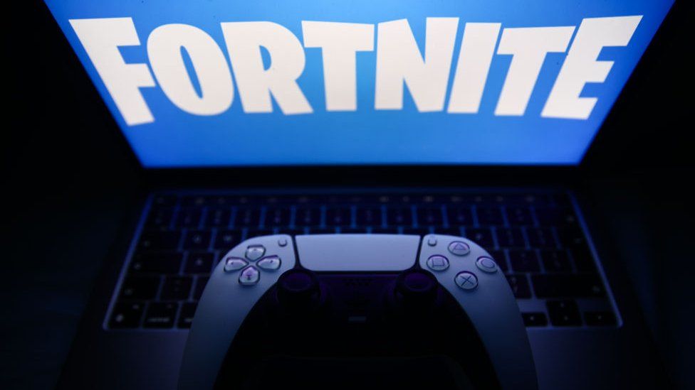 Fortnite logo displayed on a laptop screen and DualSense controller