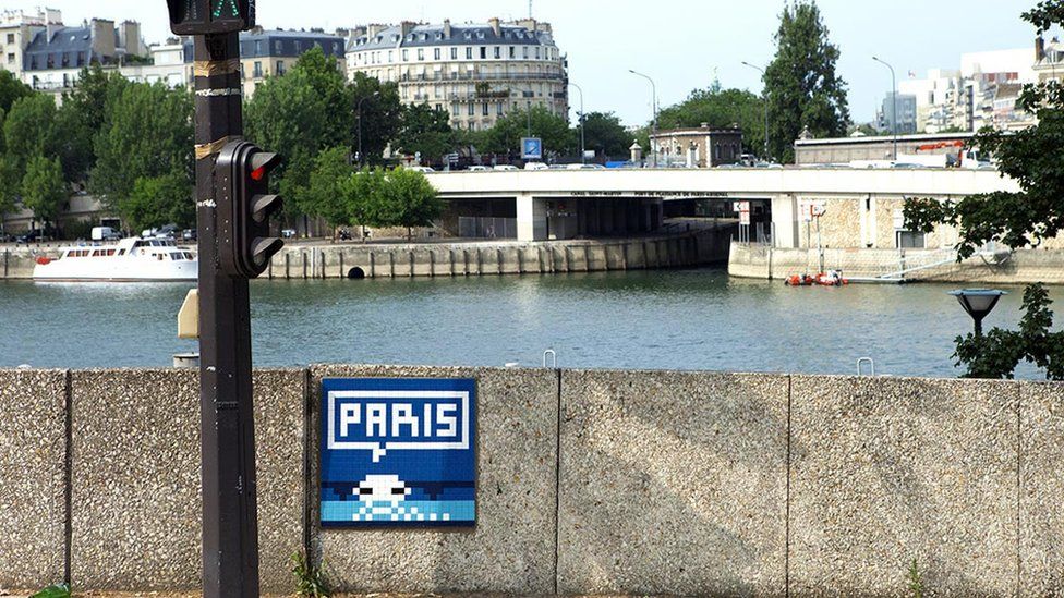 A picture of Invader's street art - a space invader with the words Paris above it