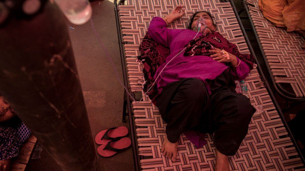 A woman wearing an oxygen mask breathes after she arrived to receive free oxygen distributed by a Gurdwara (Sikh Holy place) as a service for COVID-19-positive and other patients in need along a road on May 01, 2021 in New Delhi, India.