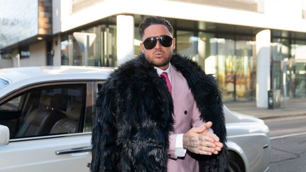 Stephen Bear dressed in a pink suit and tie with black fur coat outside Chelmsford Crown Court