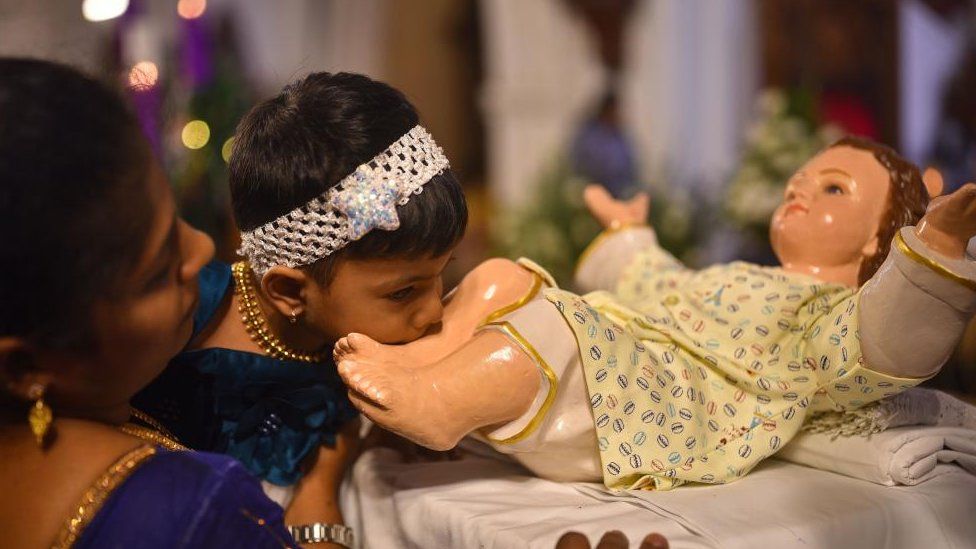 A child kisses the feet of a statue depicting the infant Jesus Christ after offering prayers during Christmas Holy Mass, at Santhome Cathedral Basilica, in Chennai, India, 25 December 2023.