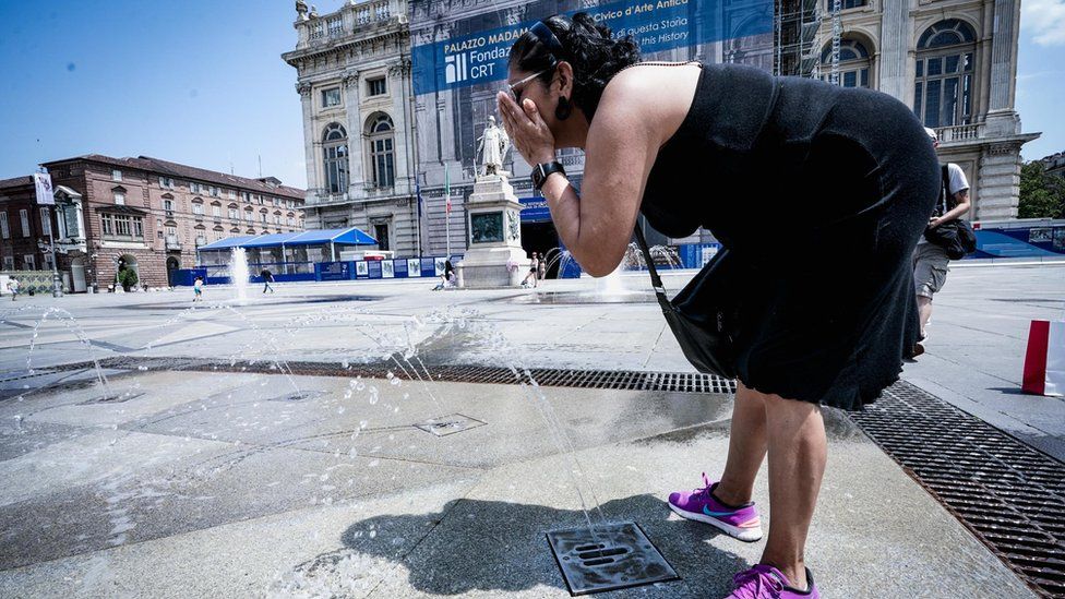 Человек охлаждается в фонтане в Турине, северная Италия