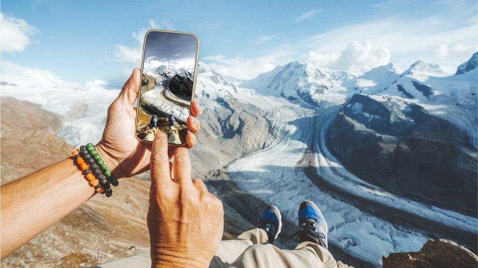 Человек фотографирует заснеженные горы