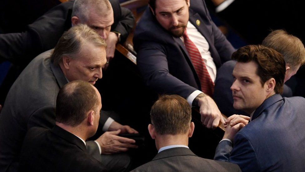 A group of politicians, including Matt Gaetz, huddle in Congress