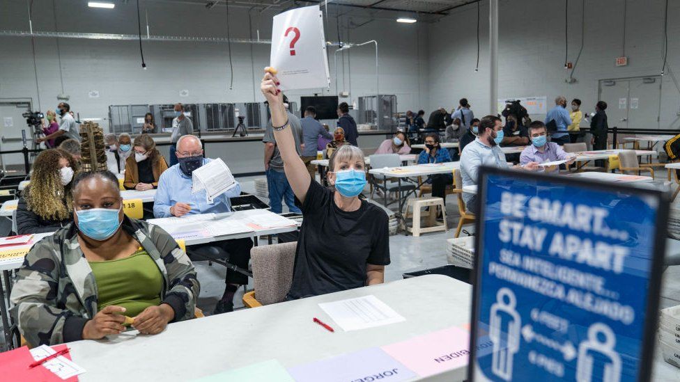 A Gwinnett county worker raises a piece of paper saying that they have a question as they begin their recount of the ballots on 13 November 2020