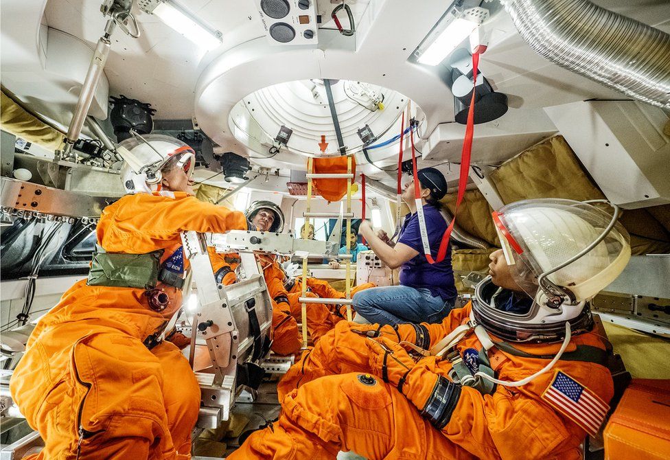 Astronauts and engineers evaluate the design of the docking hatch inside a mock-up the Orion capsule