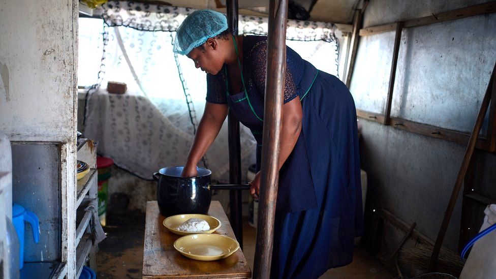 Sukoluhle Malima bending over bowls of ingredients