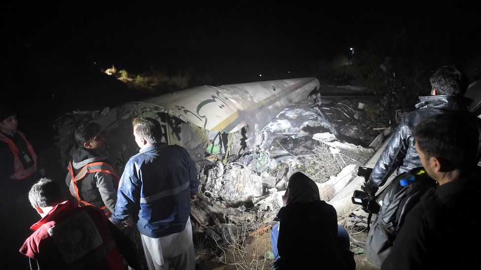Pakistani officials of Pakistan International Airlines (PIA) look at the wreckages of crashed PIA passenger plane Flight PK661 at the site