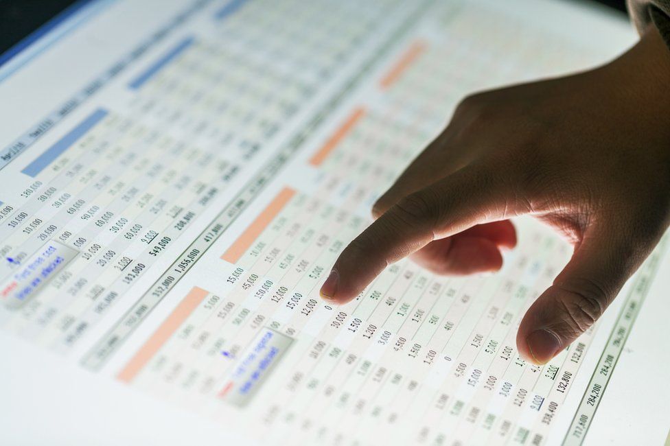 A man points at figures in a spreadsheet