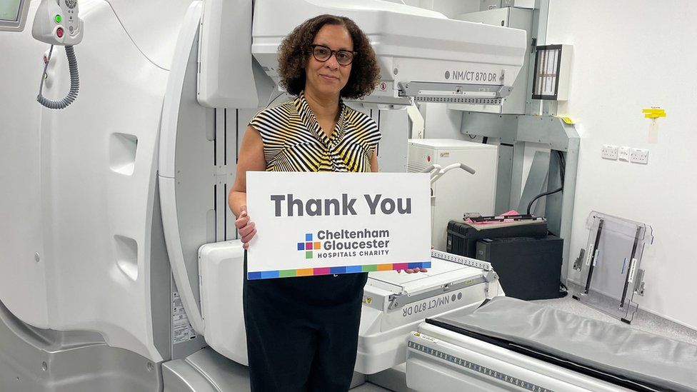 Dr Janelle Reyes-Goddard standing in front of the scanner with a thank you sign