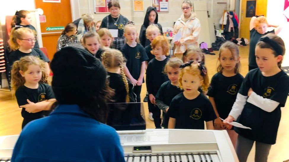 Children singing next to piano