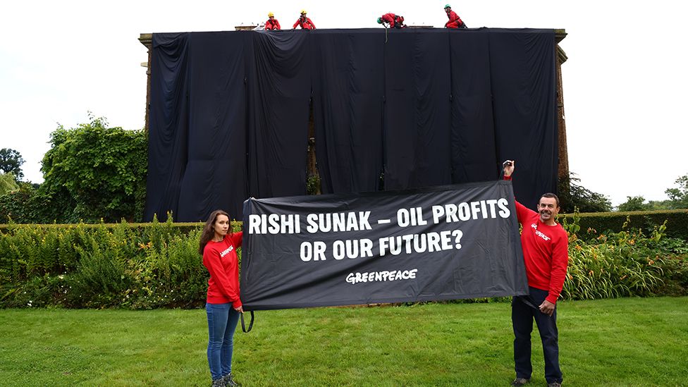 Protesters hold banner in front of house