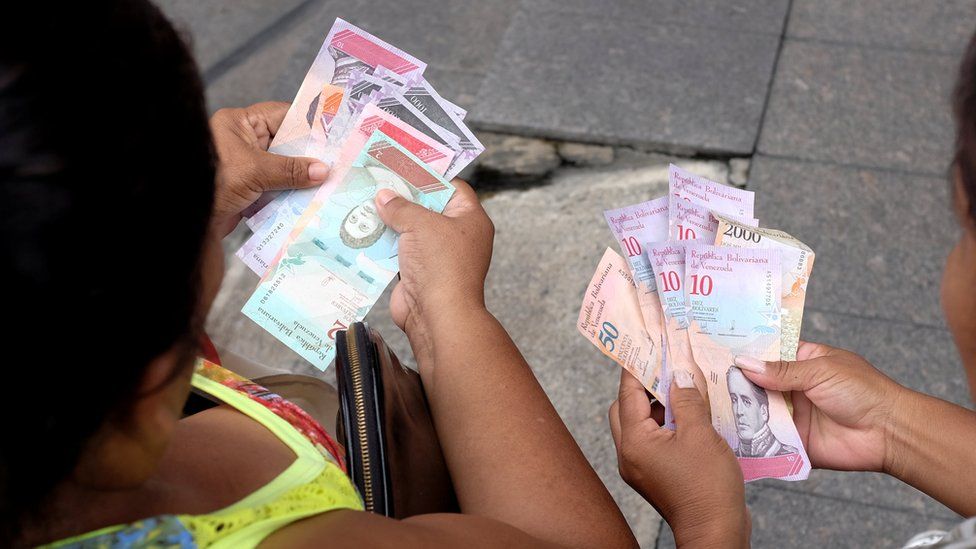 Venezuelan women hold the new currency, the sovereign bolivar, after its launch