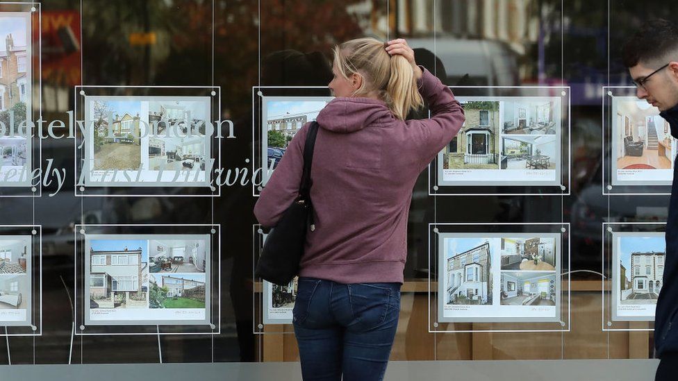 A woman looking at homes to buy at an estate agent's