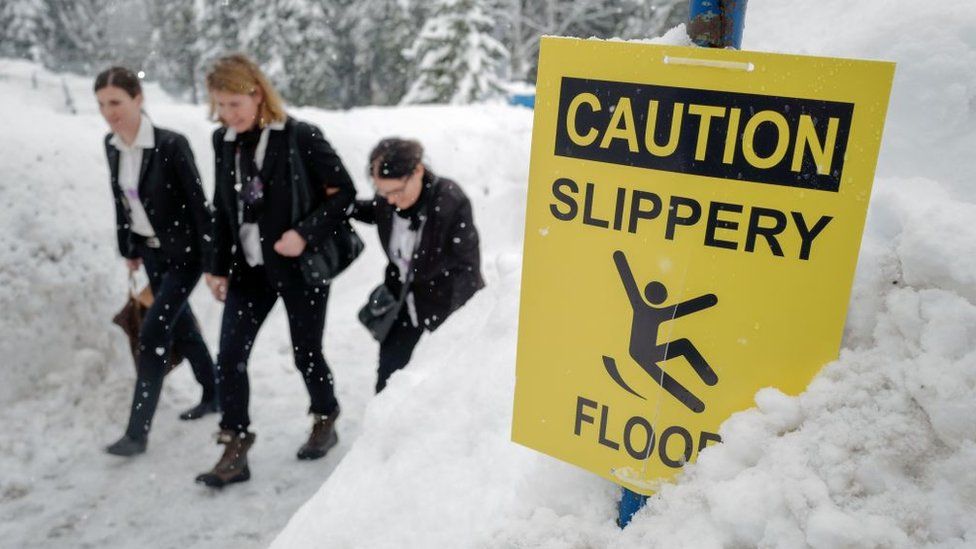 Staff members walk under snowfall next to the Congress Centre ahead of the World Economic Forum (WEF) 2018 annual meeting, on January 22, 2018 in Davos