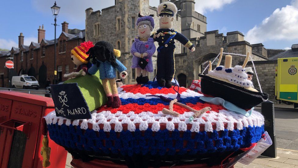 A postbox in Windsor is adorned with crocheted figures of the Queen and Prince Philip, a naval ship and two people doing the Duke of Edinburgh's Award