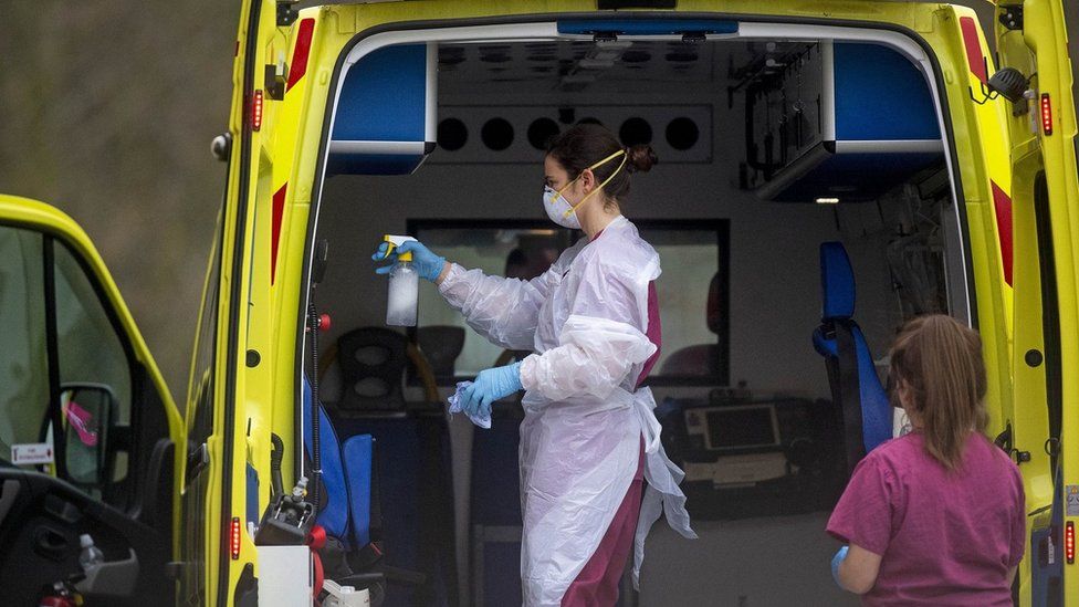 Worker wearing protective clothing cleans ambulance