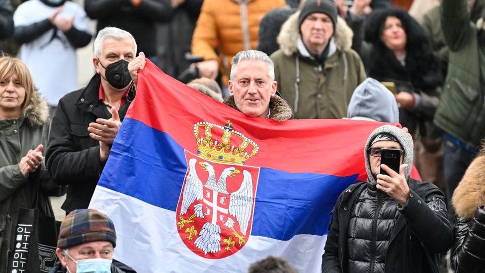 Мужчина держит сербский флаг во время митинга в поддержку Джоковича в Белграде