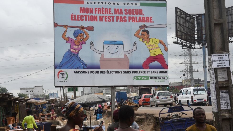 People walk past a billboard in Yopougon, a popular district of Abidjan, which promotes peaceful elections in Ivory Coast