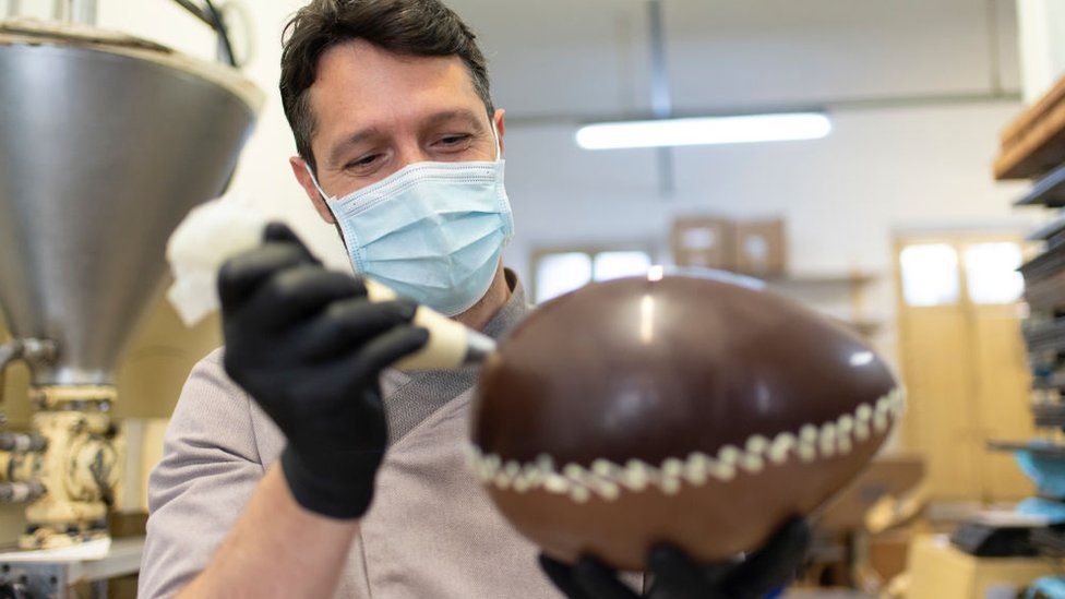 Man decorates Easter egg while wearing face mask