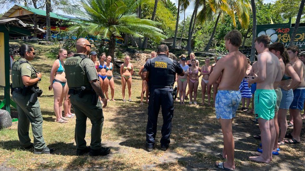 Photo of uniformed conservation officers speaking to a group of swimmers in Hawaii on land