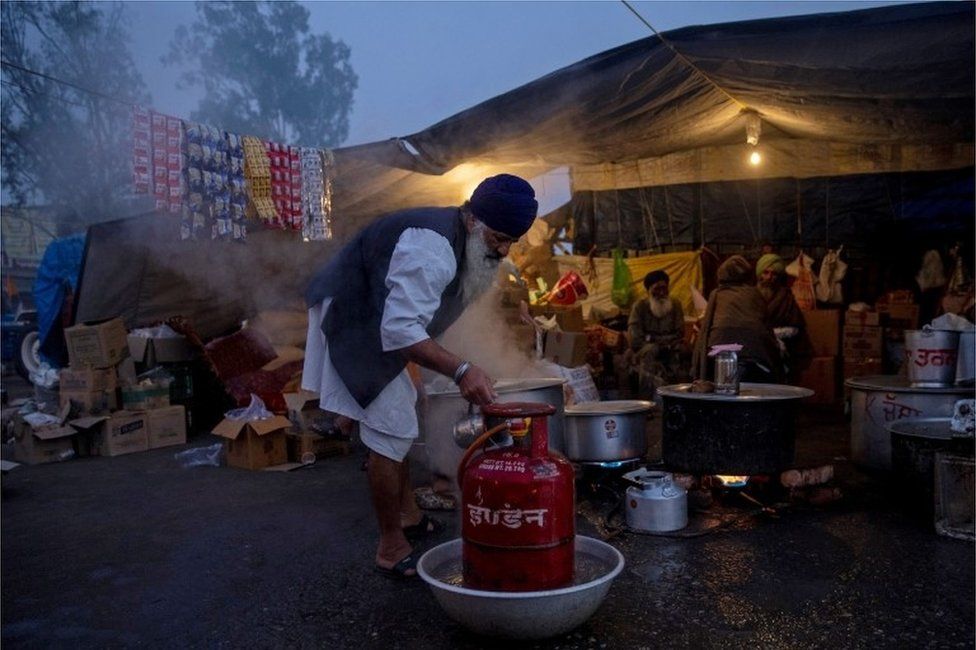 A farmer prepares meals at the site of a protest during a nationwide protest against the newly passed farm bills on a foggy morning at Singhu border near Delhi, India, December 8, 2020.
