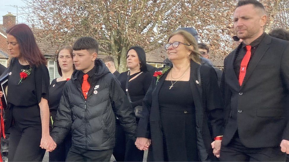 Mourners at Mr Dunn's funeral walking hand in hand and wearing red and black in memory of Mr Dunn's love of Liverpool football club