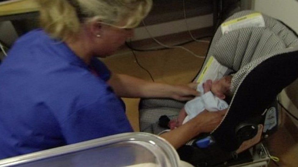 Nurse placing baby in car seat