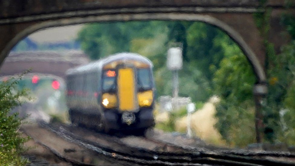 A train passes under a bridge amid a heat haze