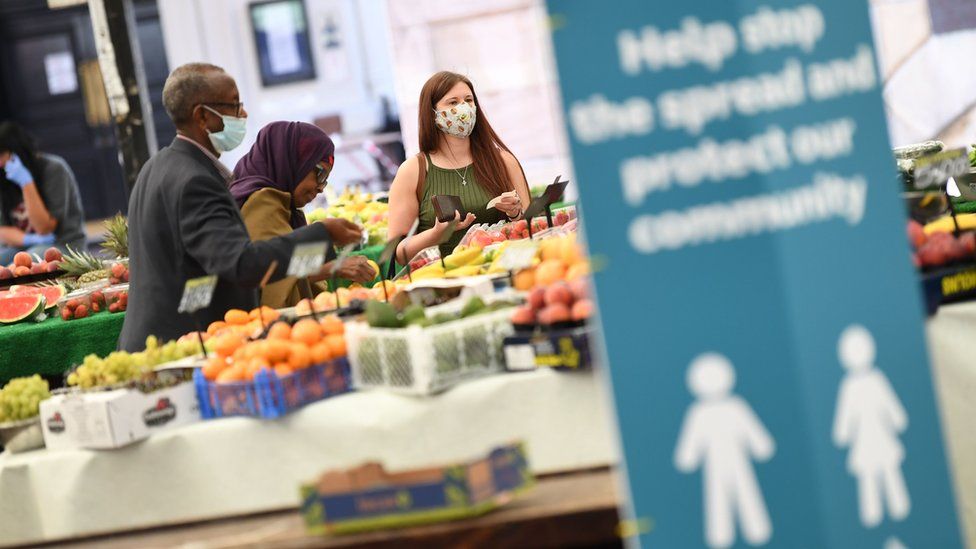 People wearing face masks as they shop at an open fruit and vegetable market in Leicester