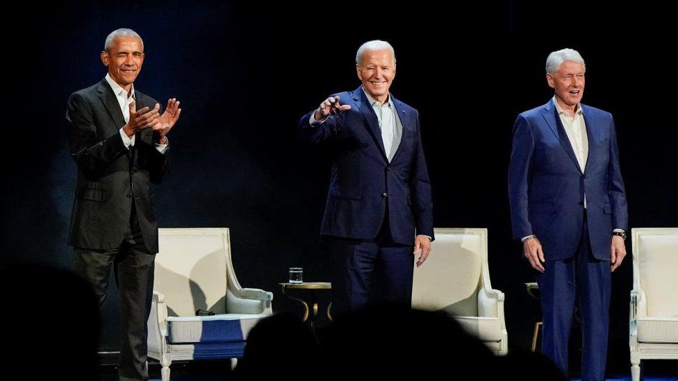 Presidents Obama, Biden and Clinton standing on stage