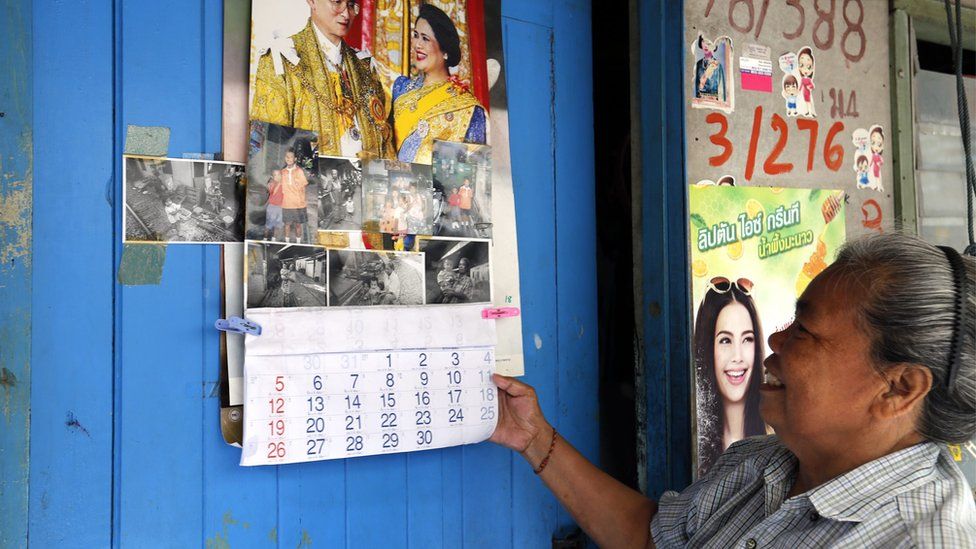 Thai woman Ling Poomuang, 61, with a calendar showing Thai King Bhumibol Adulyadej, the world's longest-reigning monarch, and his wife Thai Queen Sirikit