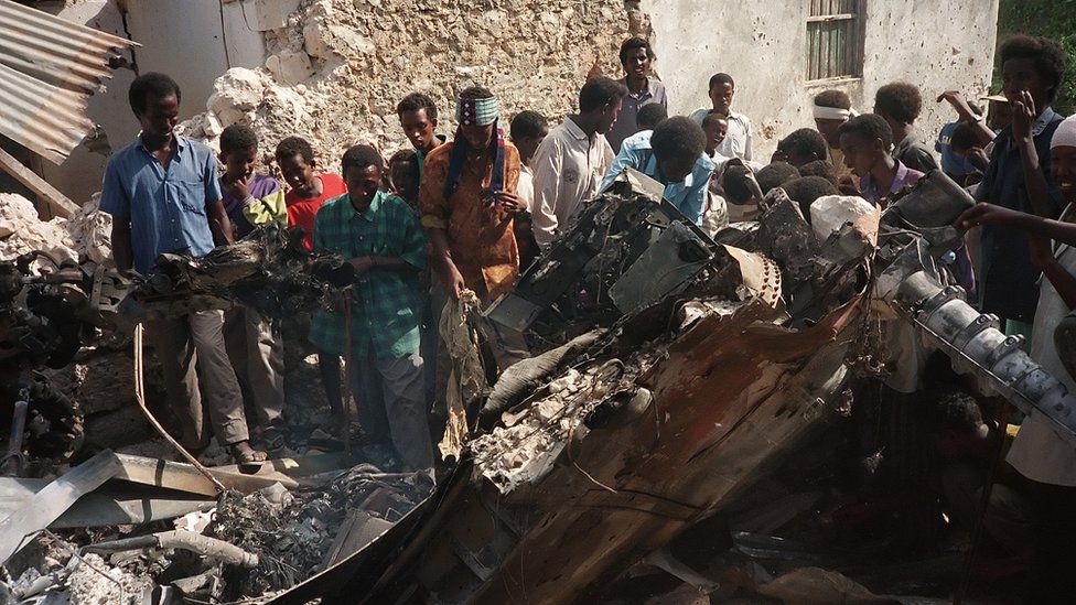 Somalis look at the wreckage of a US helicopter, in a Mogadishu street, 04 October 1993, after it was shot down.