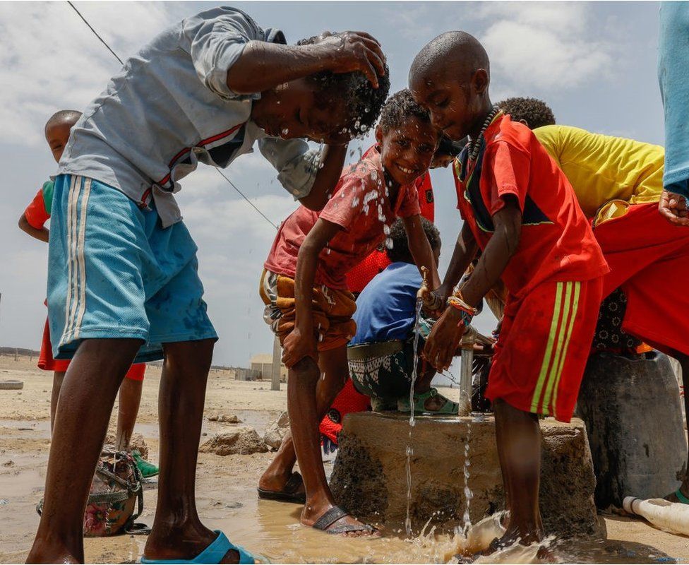 Children at a water pump washing themselves